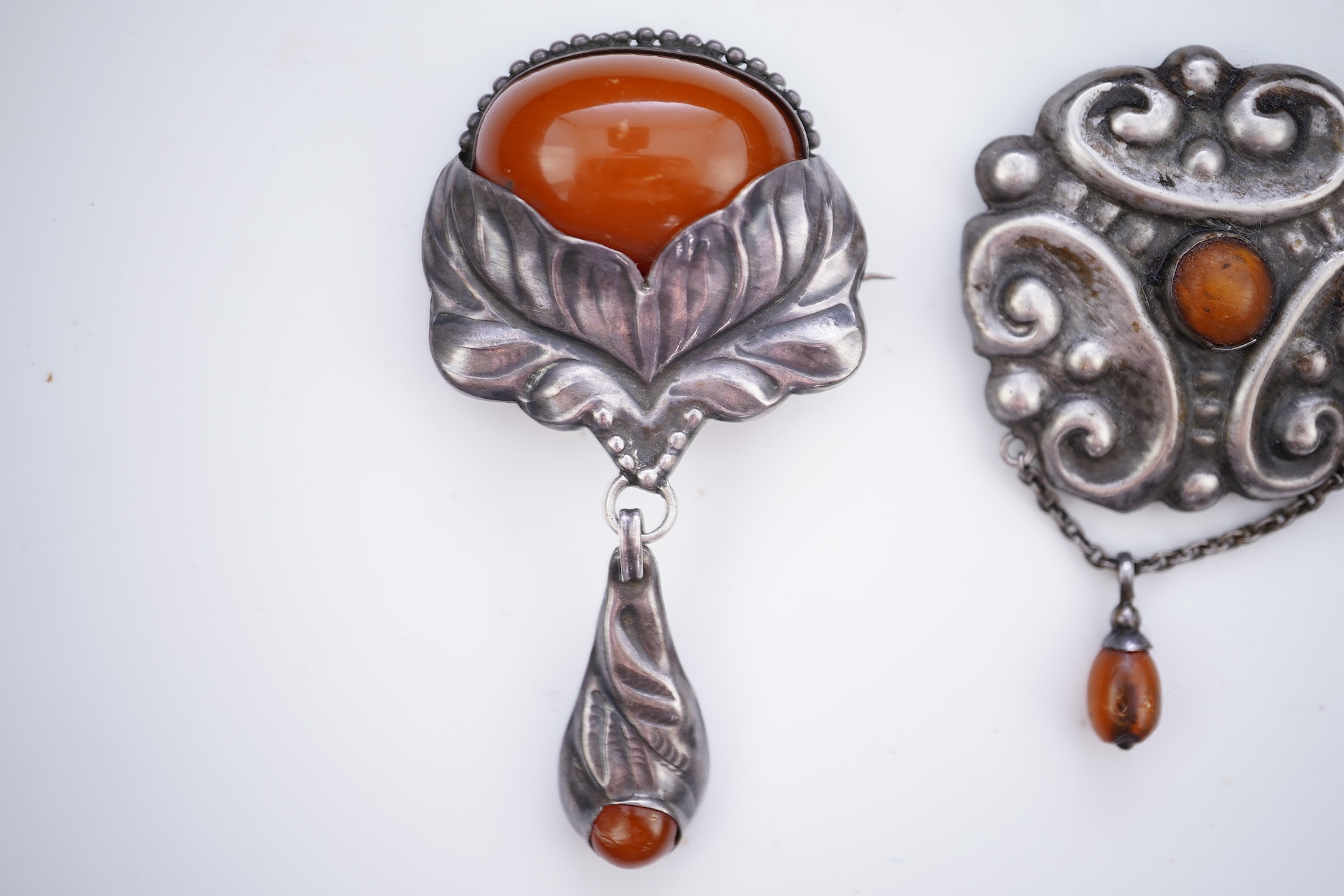 Two Arts & Crafts silver and amber pendant brooches, probably Denmark, early 20th century
